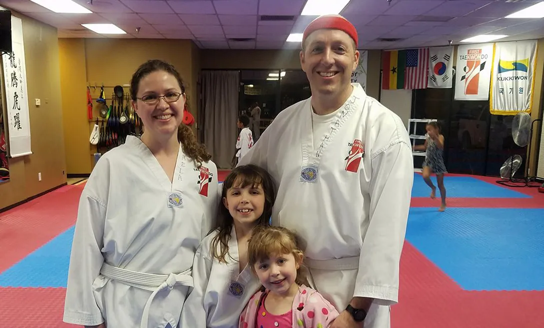 family-of-four-in-taekwondo-gear-smiling-at-dojo