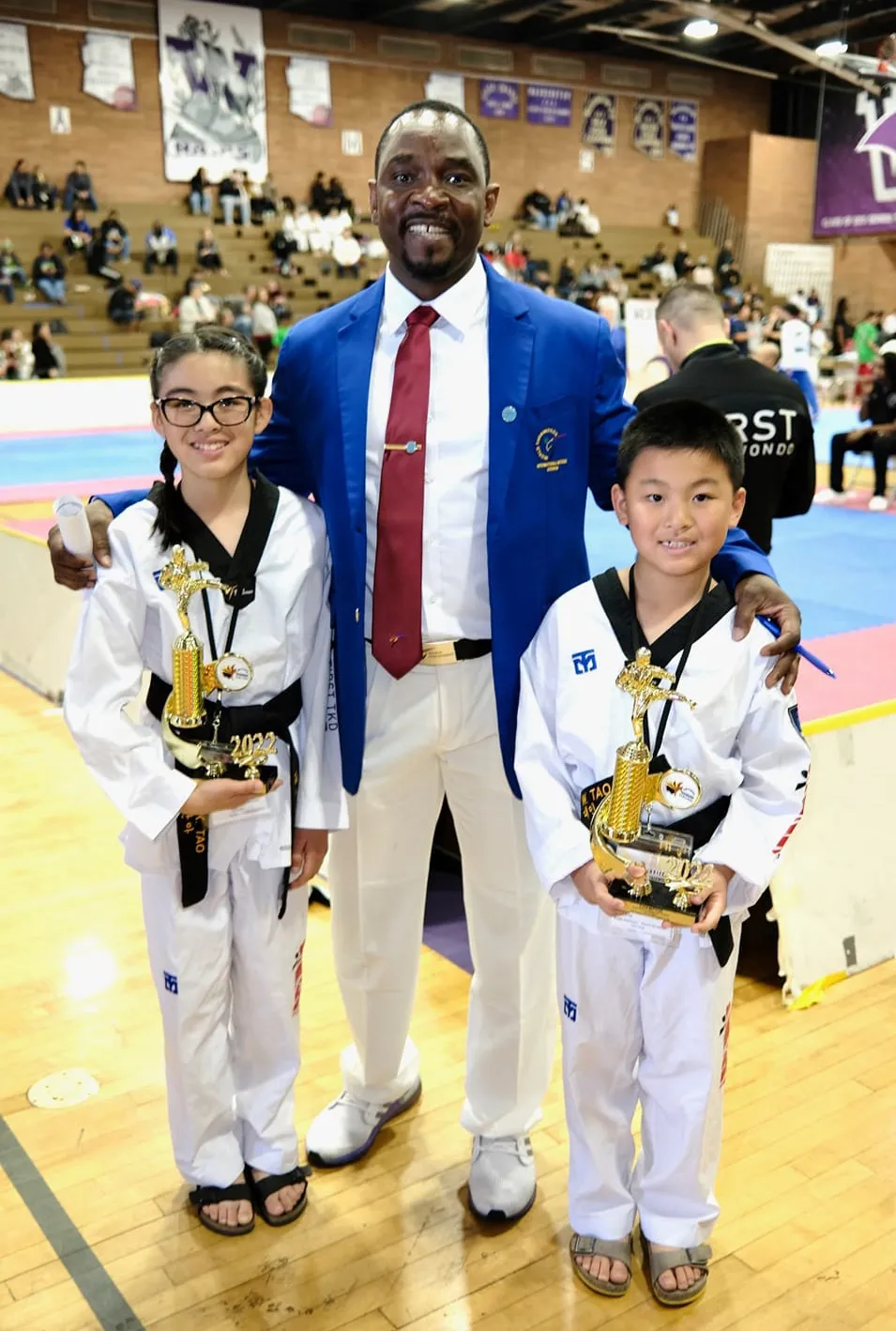 taekwondo-instructor-with-young-students-holding-trophies