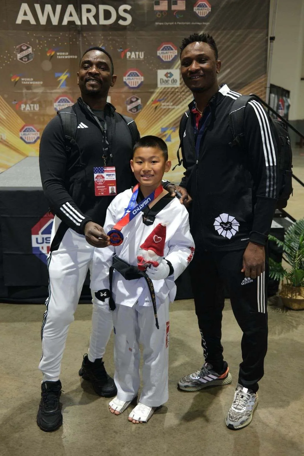 young-taekwondo-athlete-with-medal-flanked-by-two-coaches