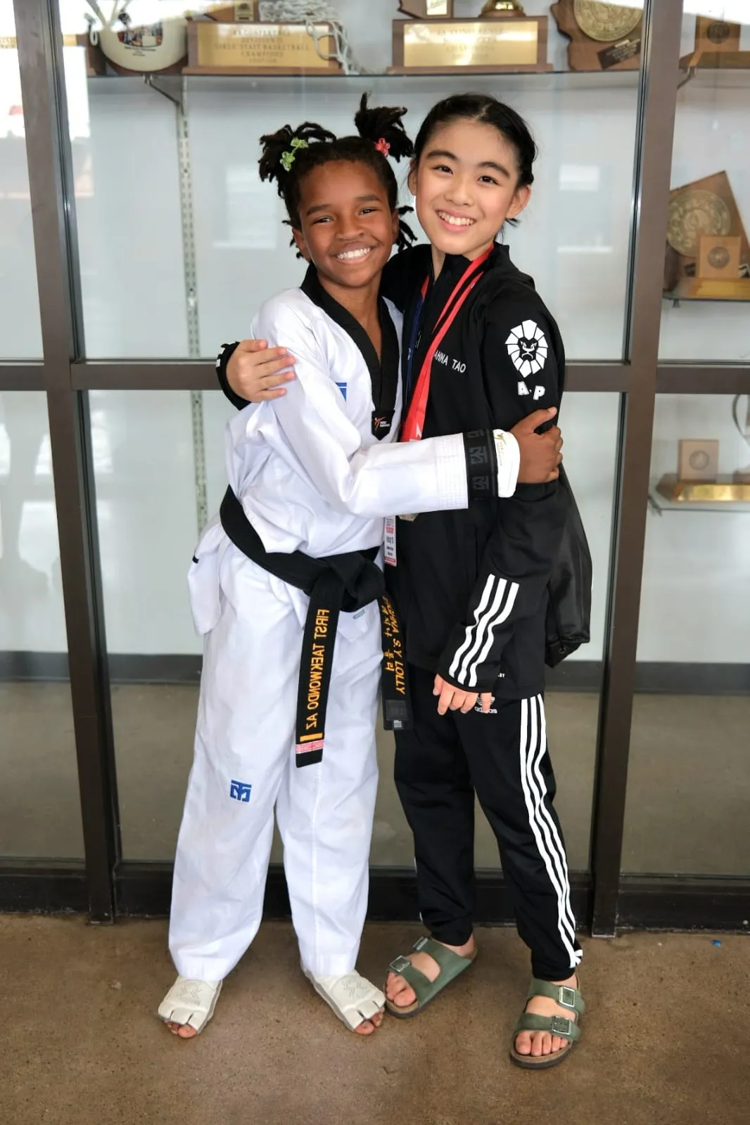two-young-girls-in-martial-arts-attire-embracing-smiling